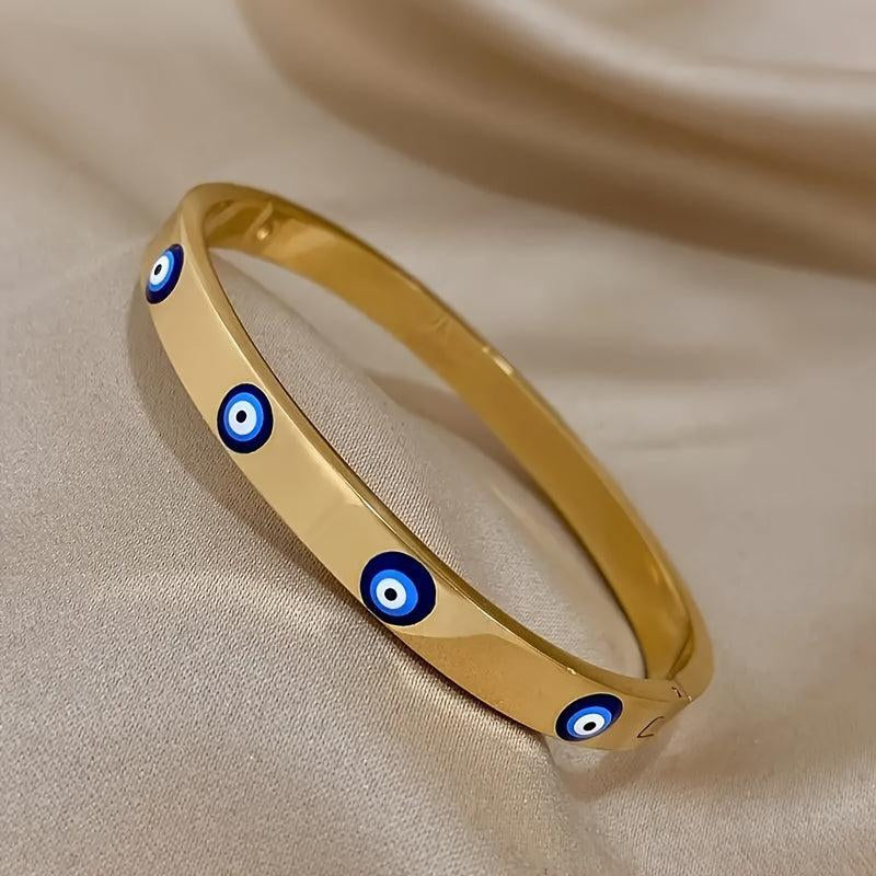 Gold bracelet with blue evil eye charms on a beige fabric background