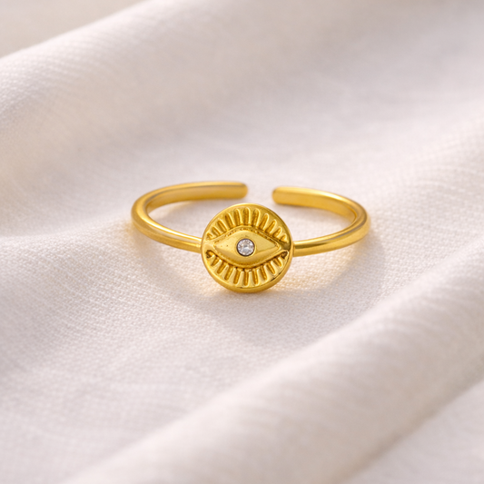 Gold ring with a circular design on a white fabric background