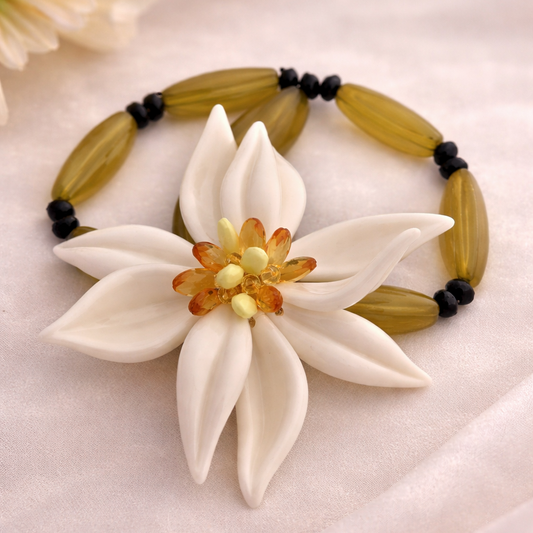 Bracelet with a white flower-shaped clasp on a light pink fabric background