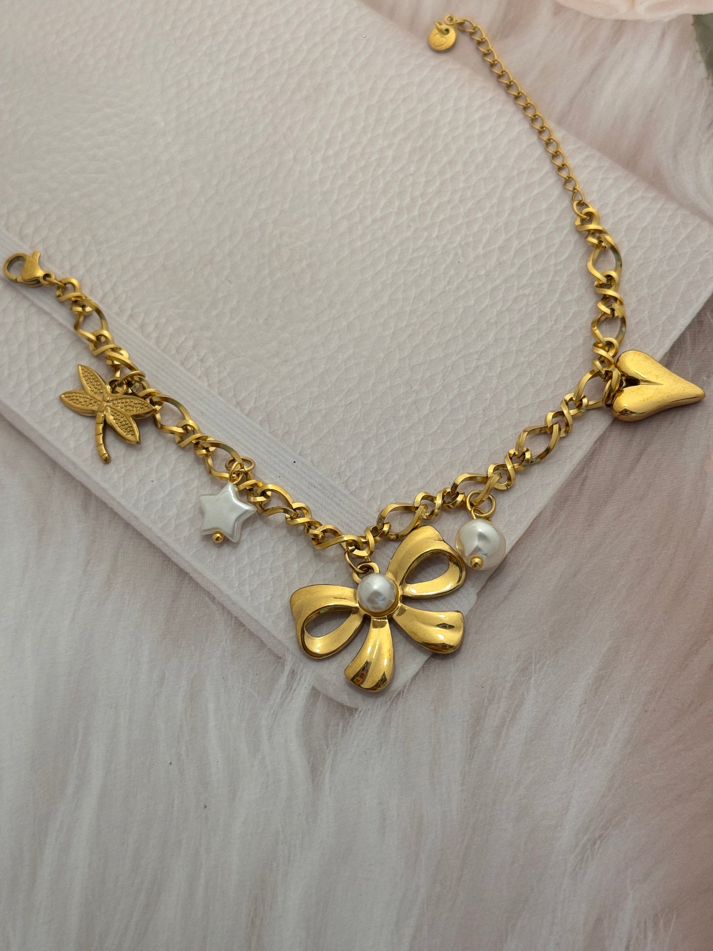 Gold bracelet with floral design and pearl beads on a light background