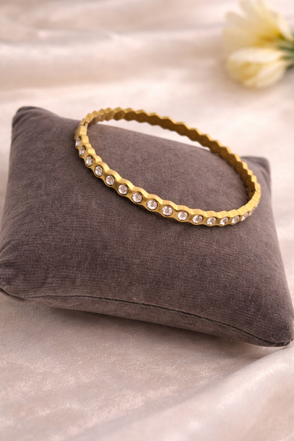 Gold bracelet with crystals on a gray cushion