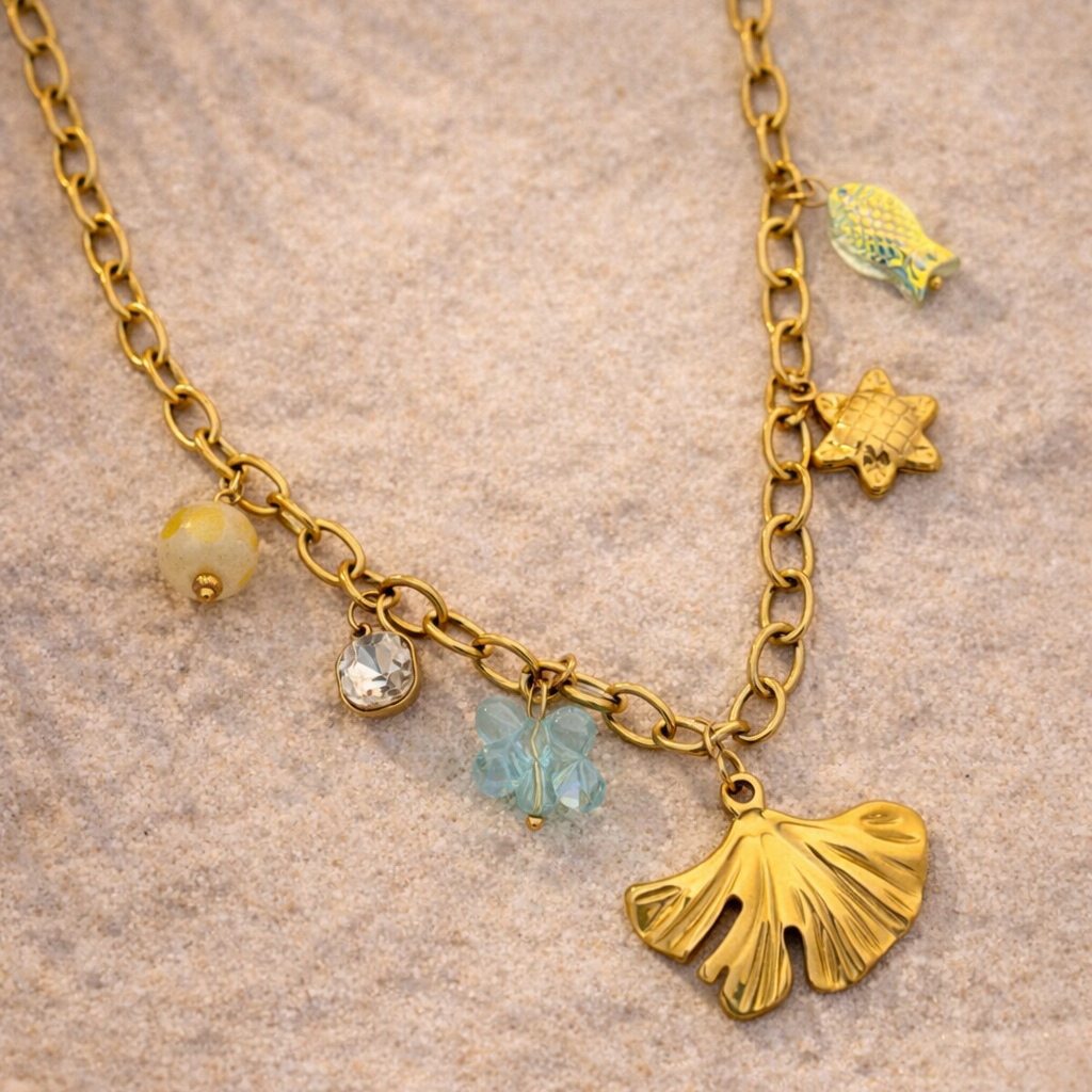 Gold necklace with various charms on a sandy background