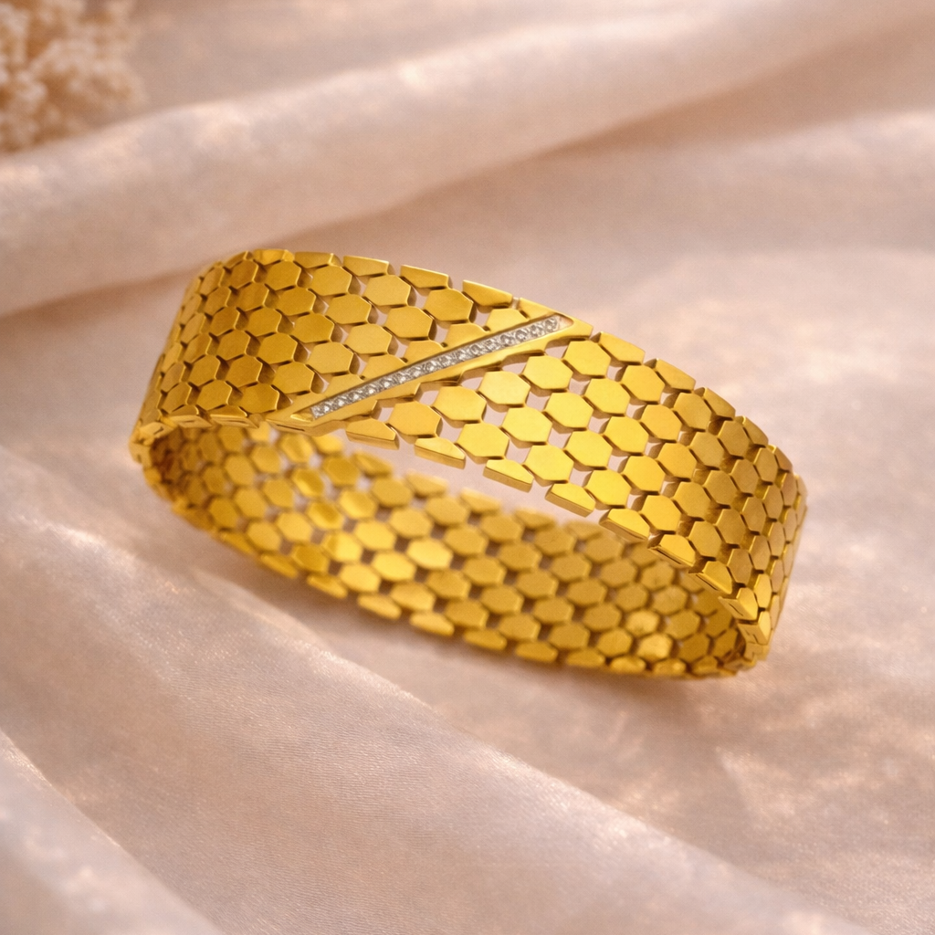 Gold bracelet with honeycomb pattern on a beige fabric background