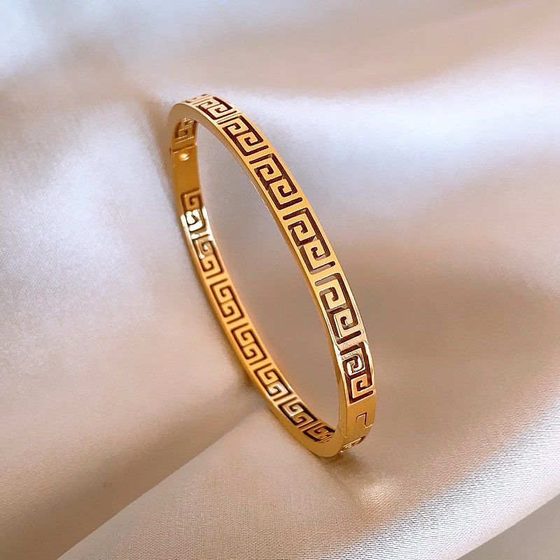 Gold bracelet with intricate pattern on a soft fabric background