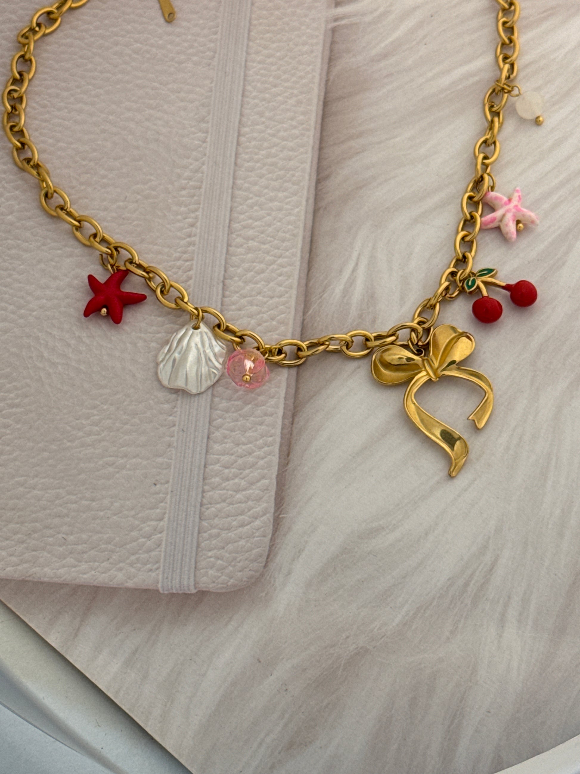 Gold chain with colorful charms on a textured surface