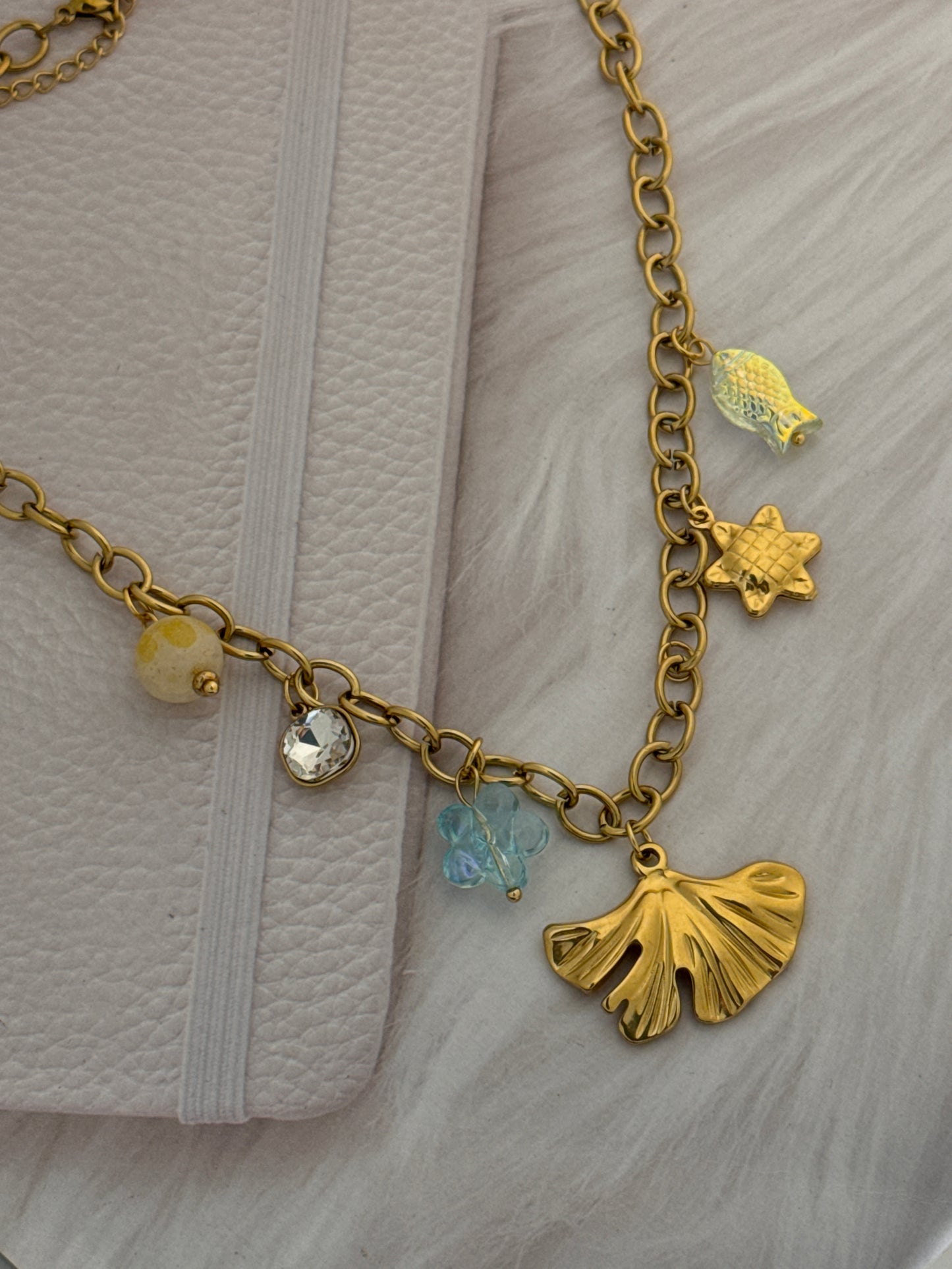 Gold bracelet with various charms on a textured surface
