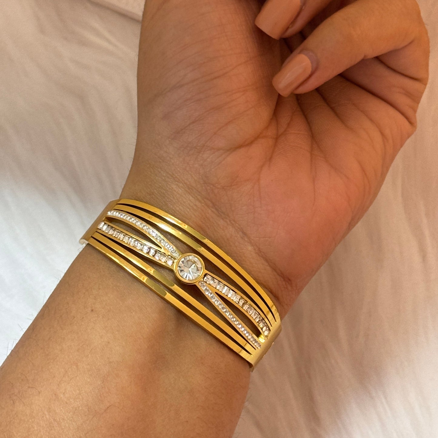 Gold bracelets on a wrist with a neutral background