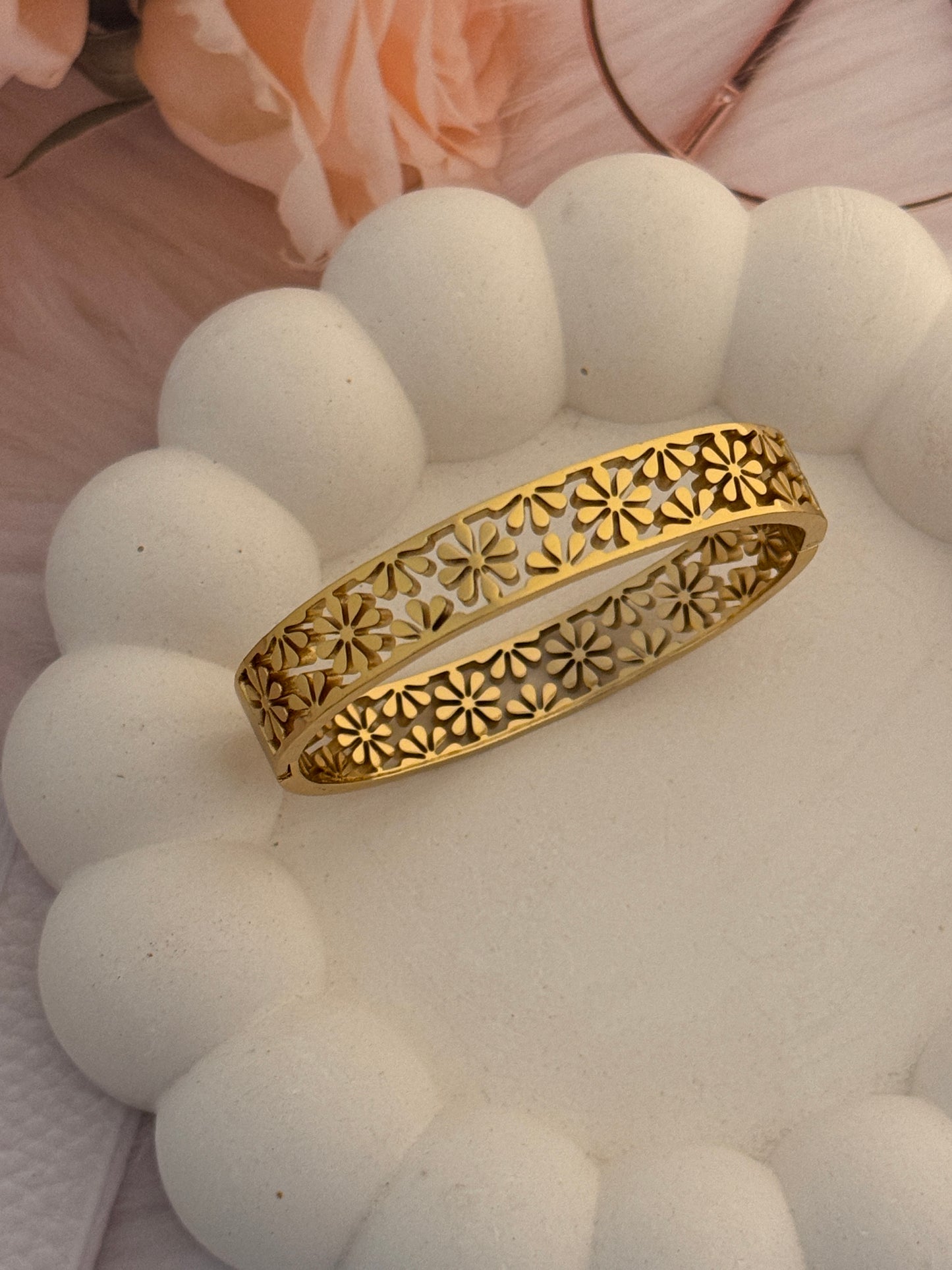Gold bracelet with intricate design on a white surface
