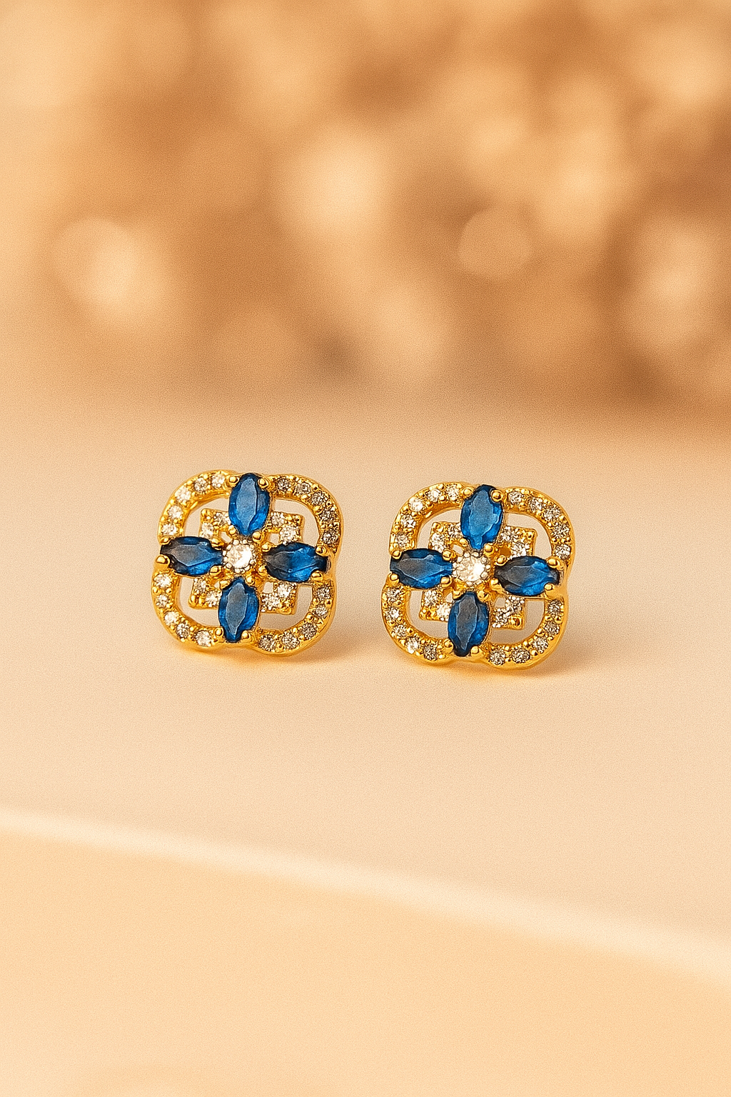 Gold earrings with blue gemstones on a beige background