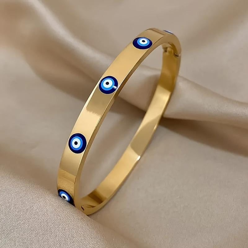 Gold bracelet with blue evil eye charms on a beige fabric background