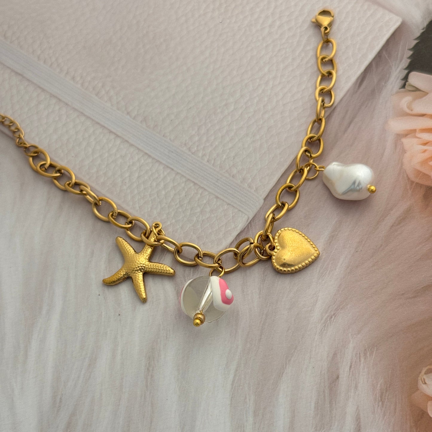Gold bracelet with starfish charm on a textured surface