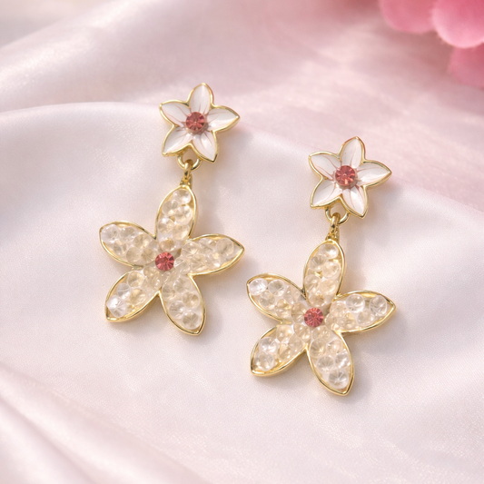 Flower-shaped earrings with gold accents on a pink satin background