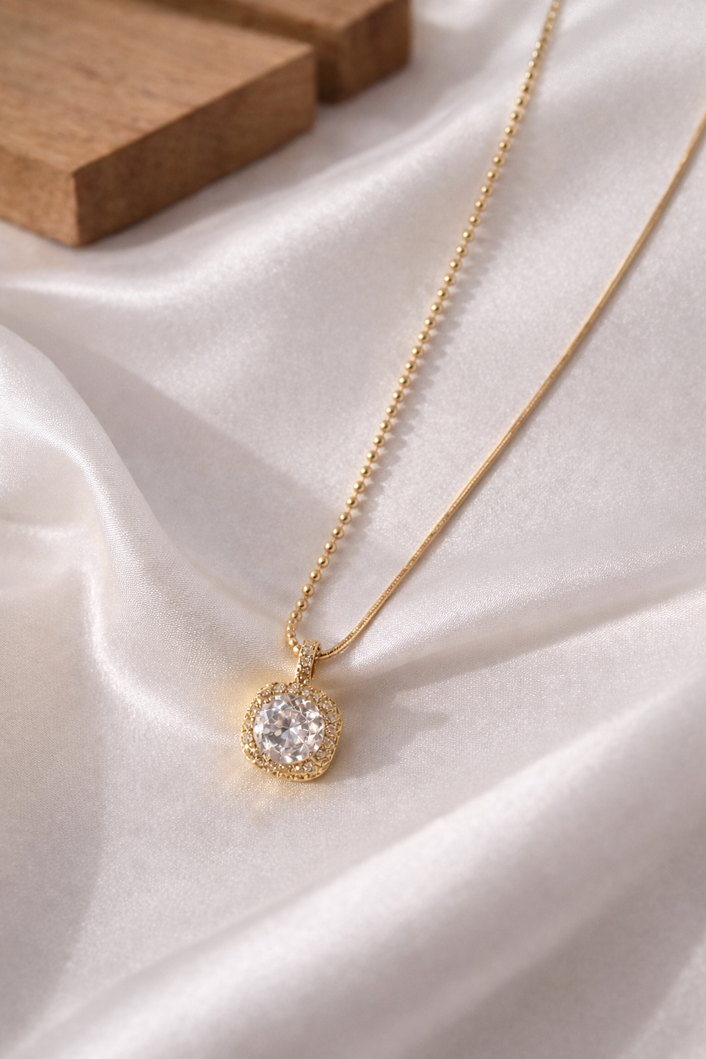 Gold necklace with a diamond pendant on a white fabric background