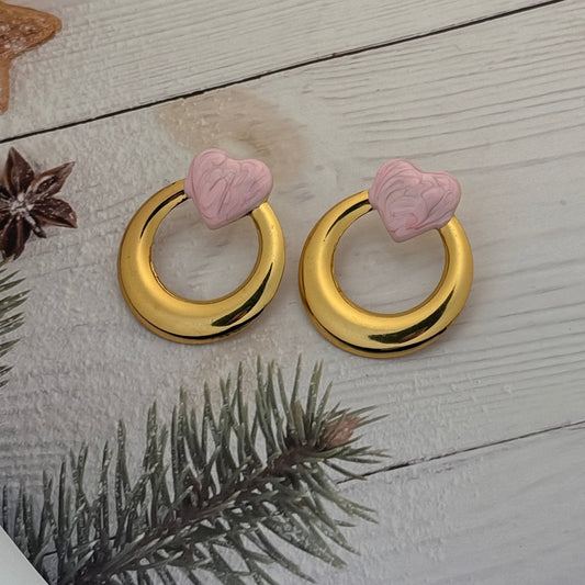 Gold door handles with pink heart-shaped knobs on a wooden surface with decorative elements.