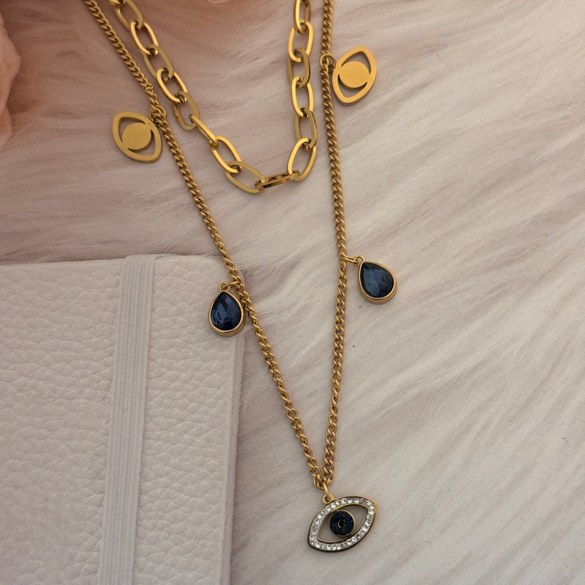 Gold chain necklace with black gemstones on a textured white surface.