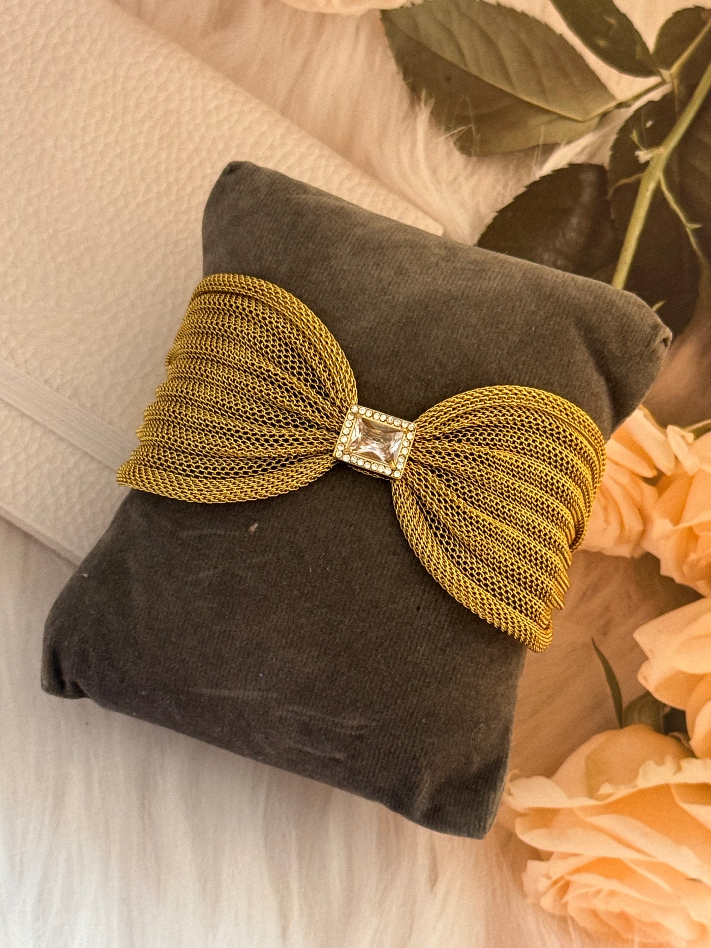 Gold bow-shaped decorative item on a brown pillow with flowers in the background