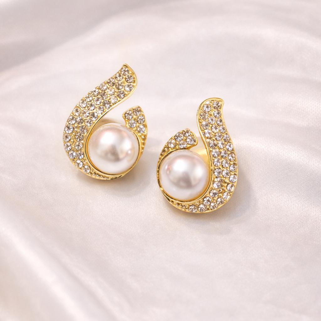 Gold earrings with pearls on a white satin background