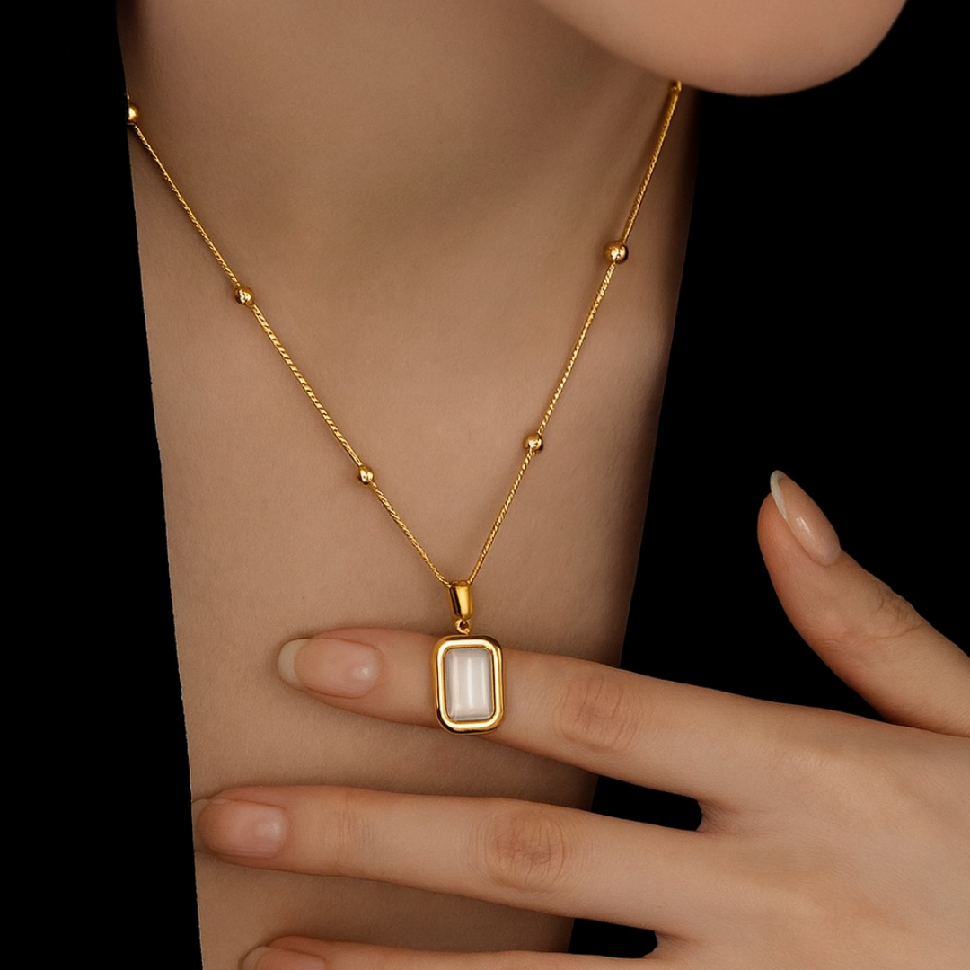 Gold necklace with a pendant on a person's neck against a black background