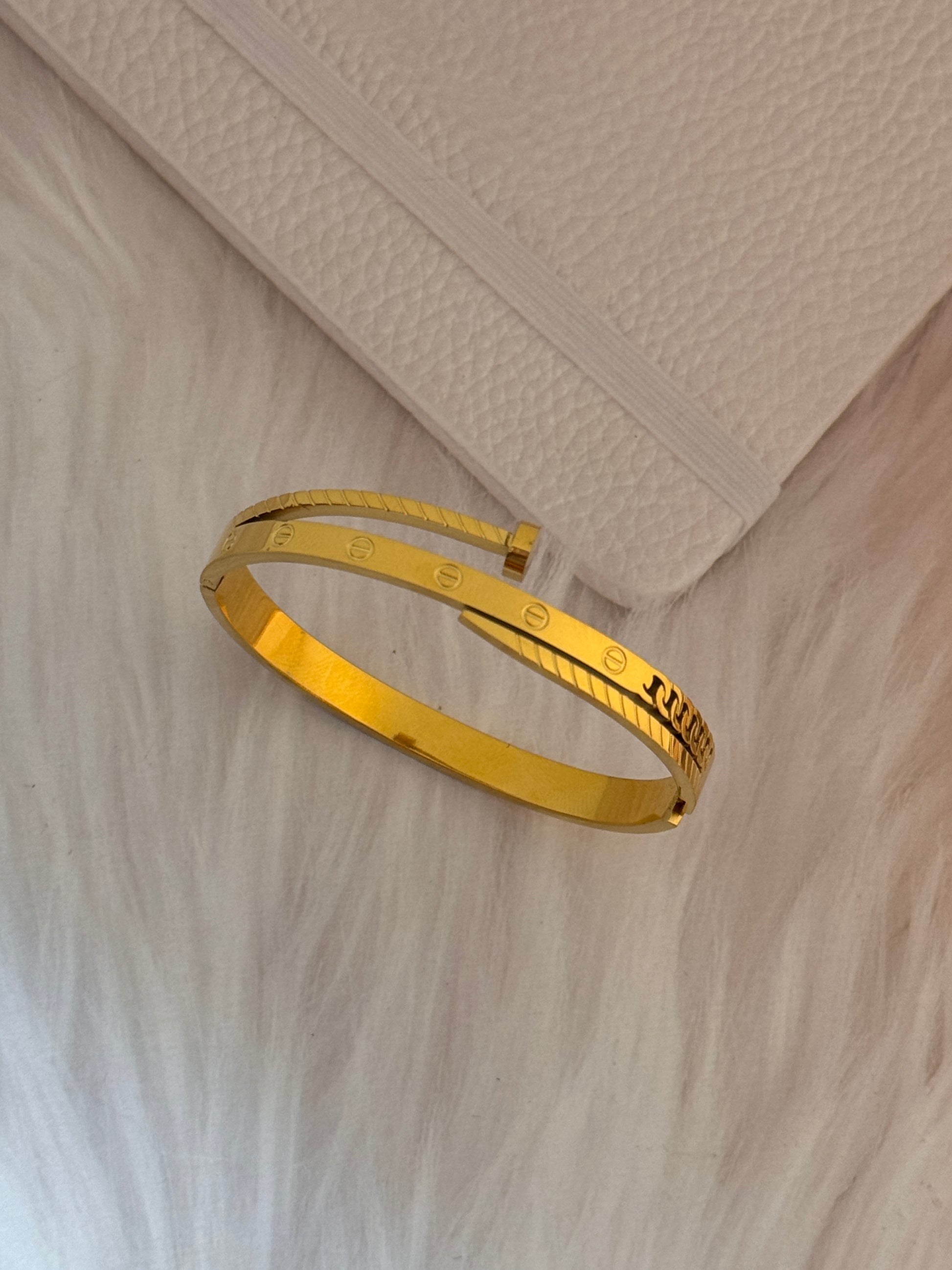 Gold bracelet on a textured beige surface