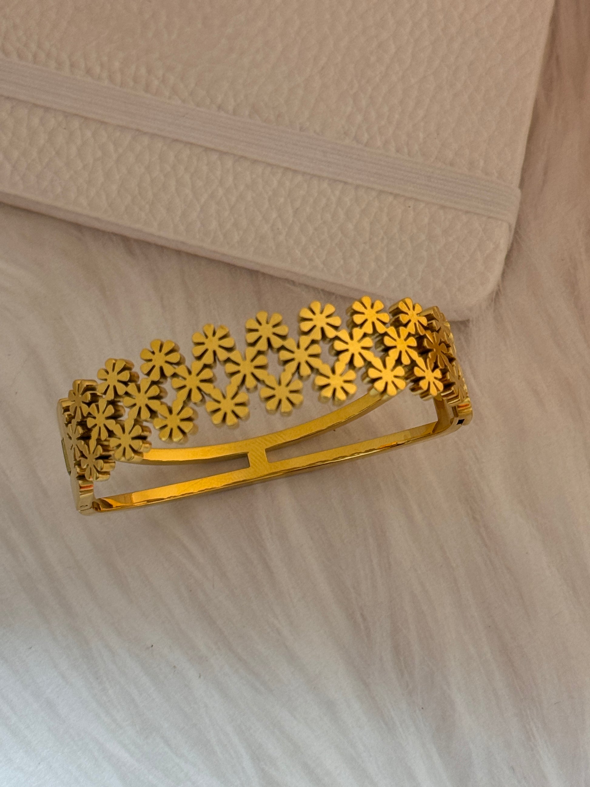 Gold hair clip with floral design on a textured beige background