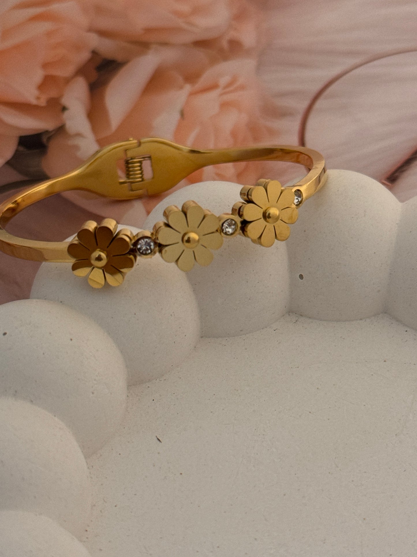 Gold bracelet with floral designs on a textured surface