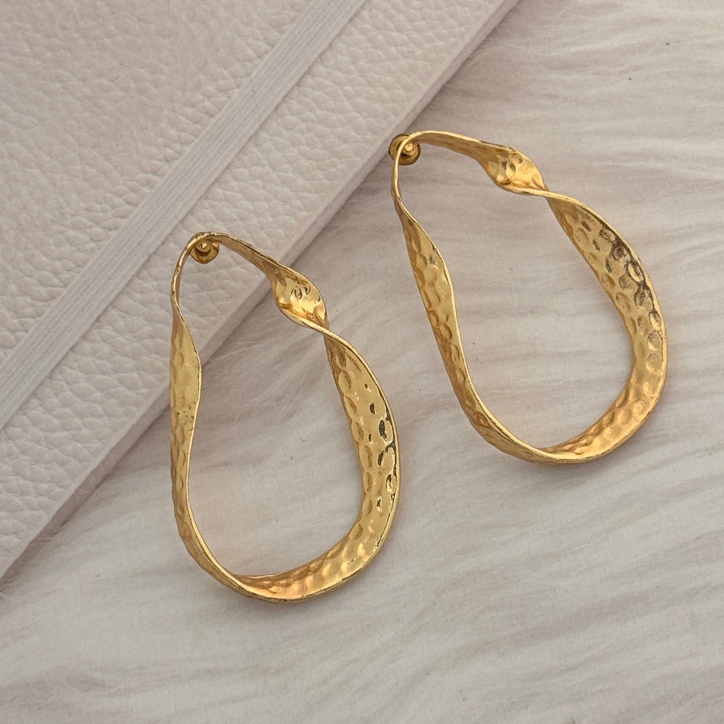 Pair of gold hoop earrings on a textured surface