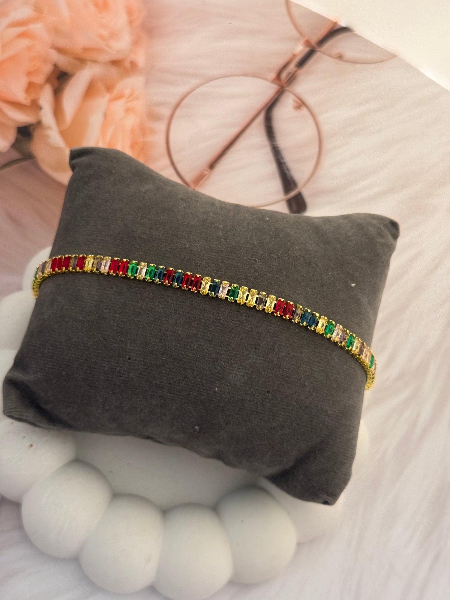 Multicolored beaded bracelet on a gray pillow with blurred background