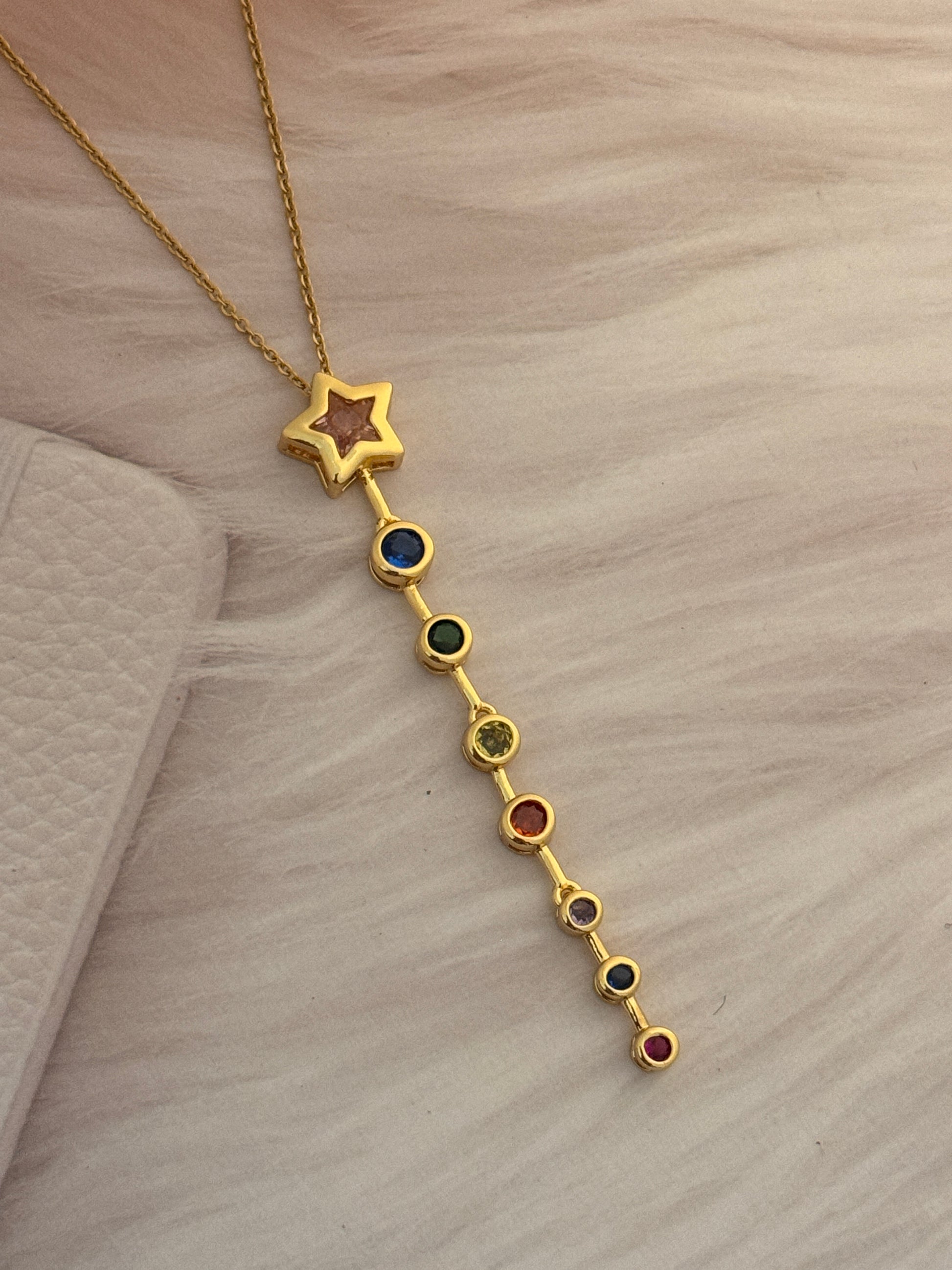 Gold bracelet with star and colorful beads on a light brown surface