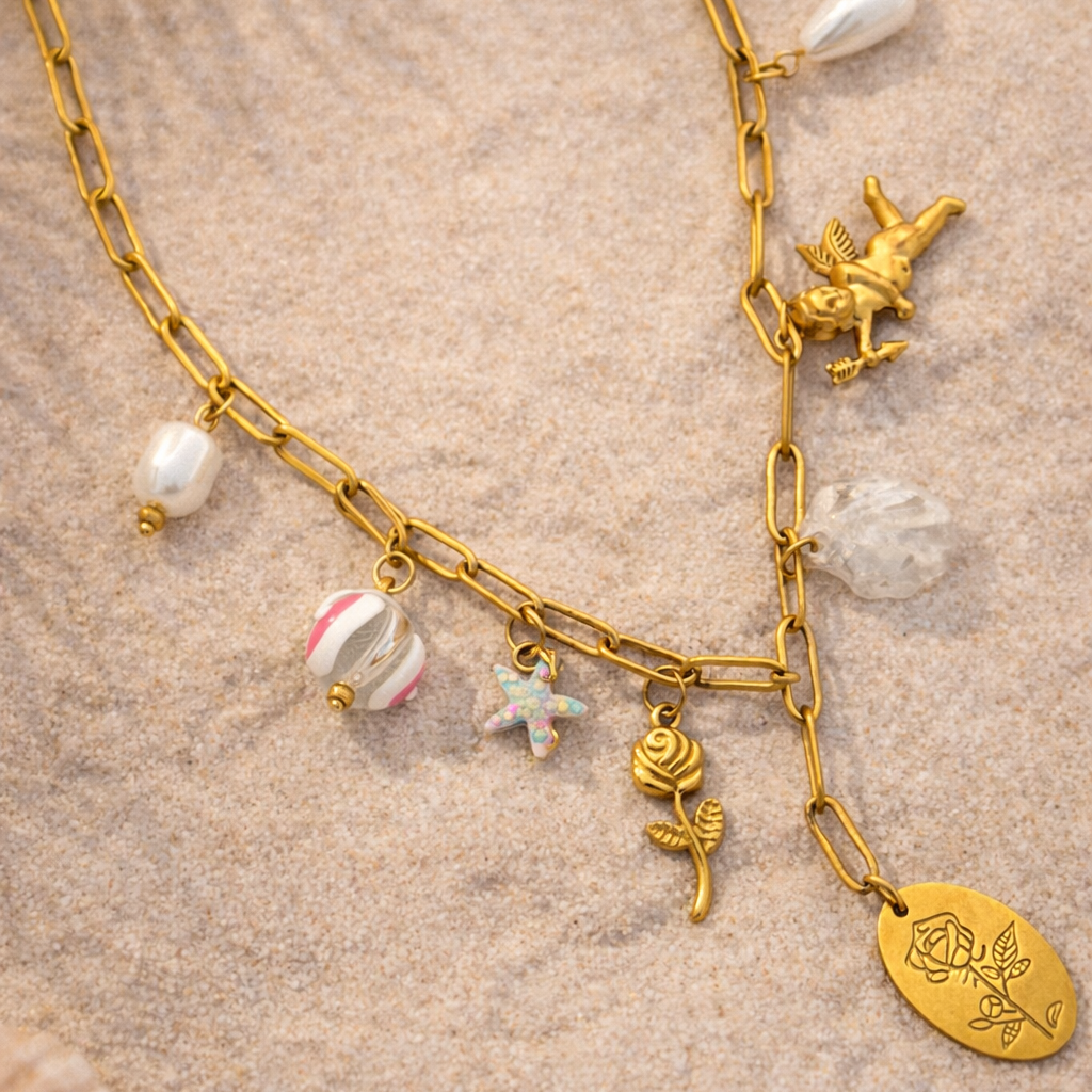 Gold necklace with various charms on a sandy background
