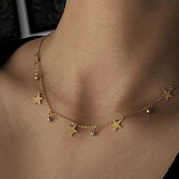 Gold necklace with star-shaped pendants on a person's neck