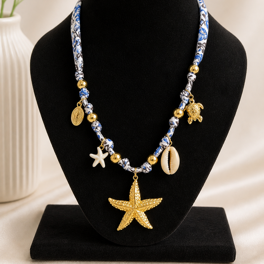 Necklace with starfish, shell, and turtle charms on a black bust with a white background