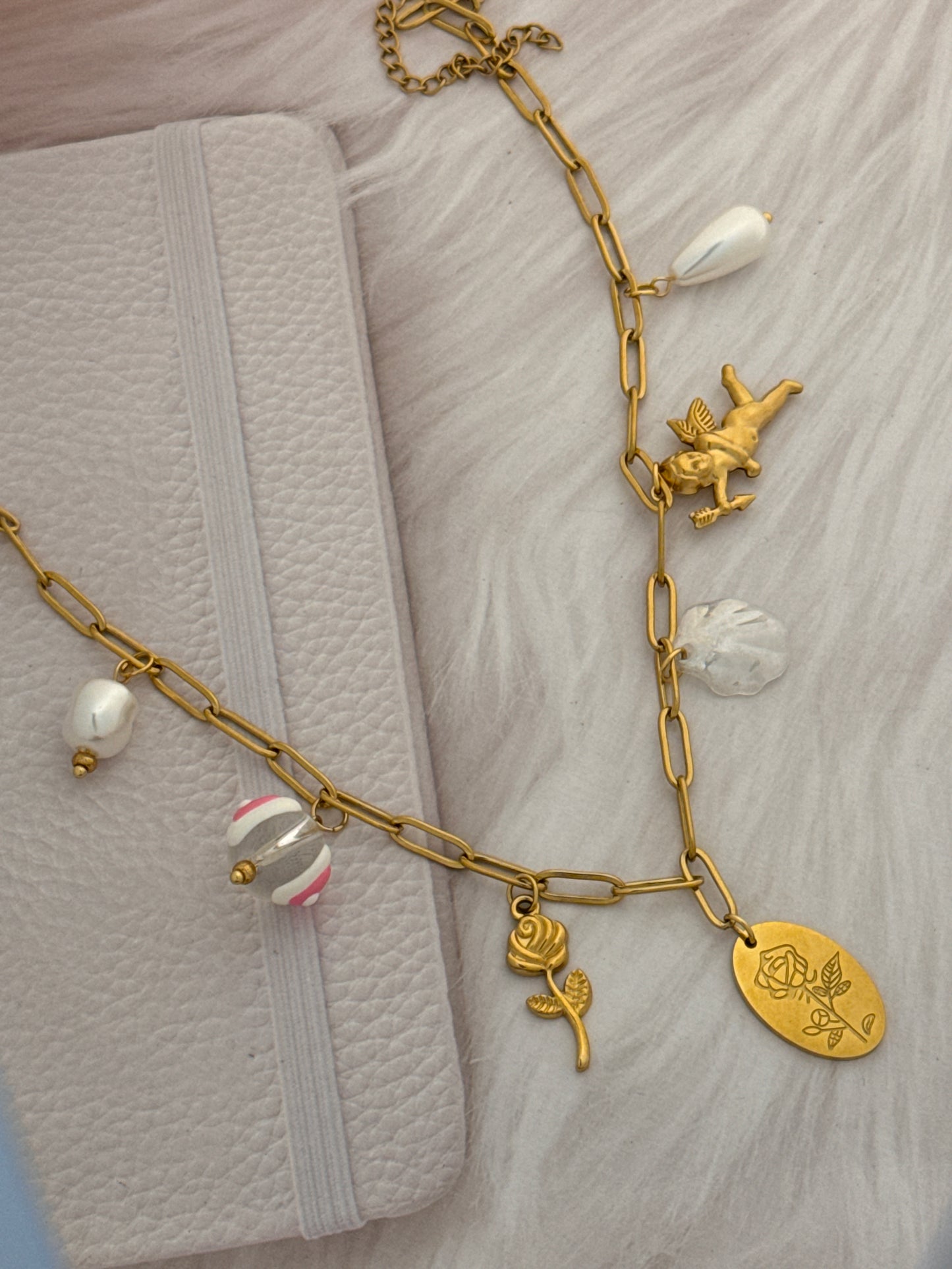 Gold chain bracelet with various charms on a textured surface