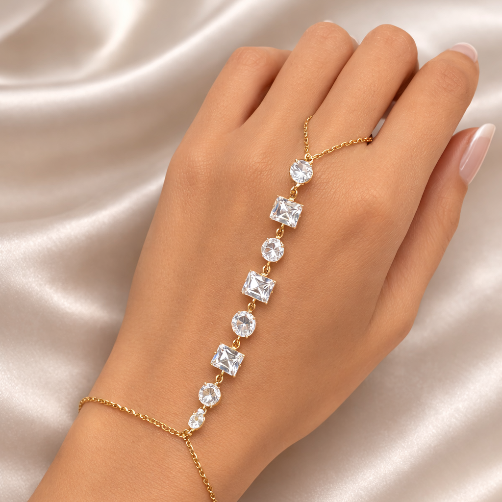 Hand wearing a gold bracelet with clear stones on a satin background