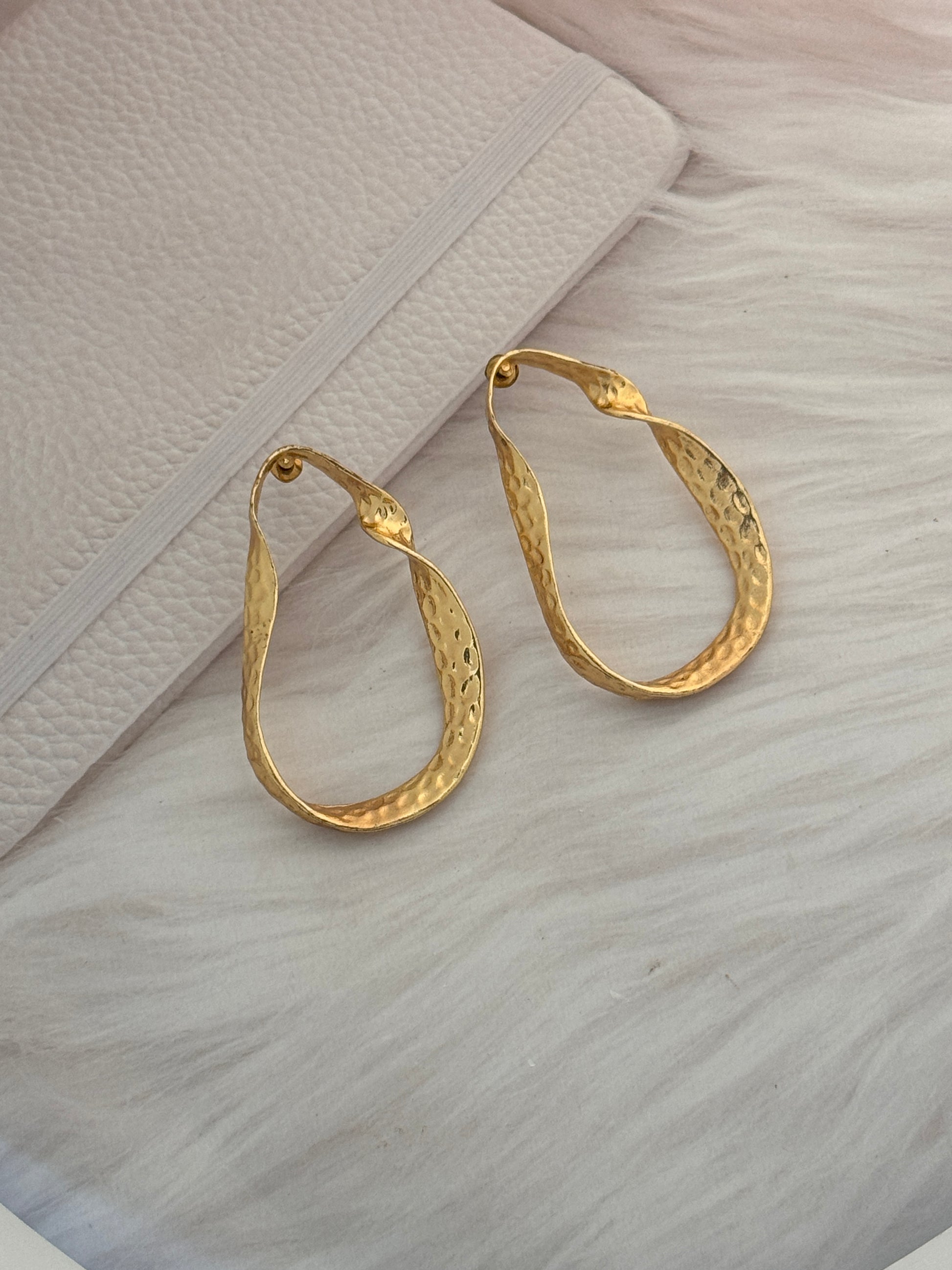 Gold hoop earrings on a textured surface
