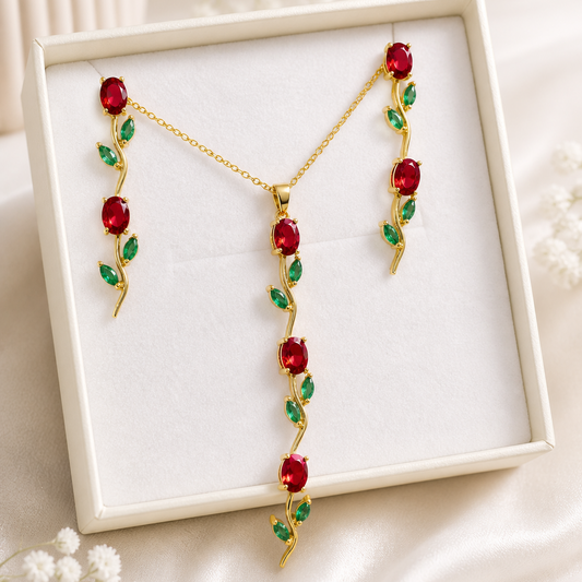 Jewelry set with red and green stones in a white box on a light background