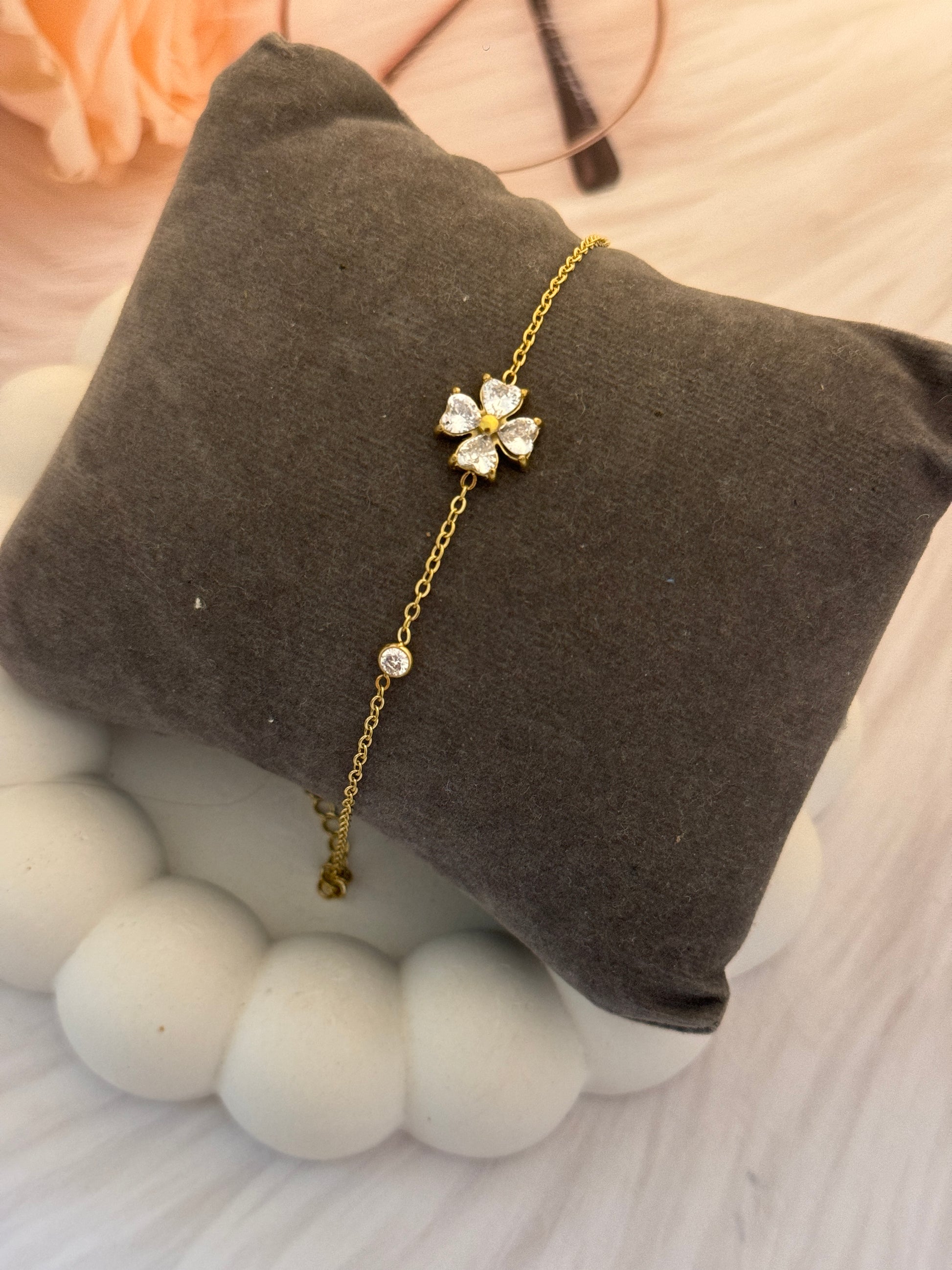 Gold bracelet with a floral clasp on a brown cushion