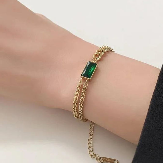 Gold bracelet with a green gemstone on a wrist, with a black box labeled 'Vip' in the background.