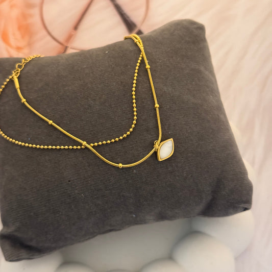 Gold bracelet with a stone on a gray cushion