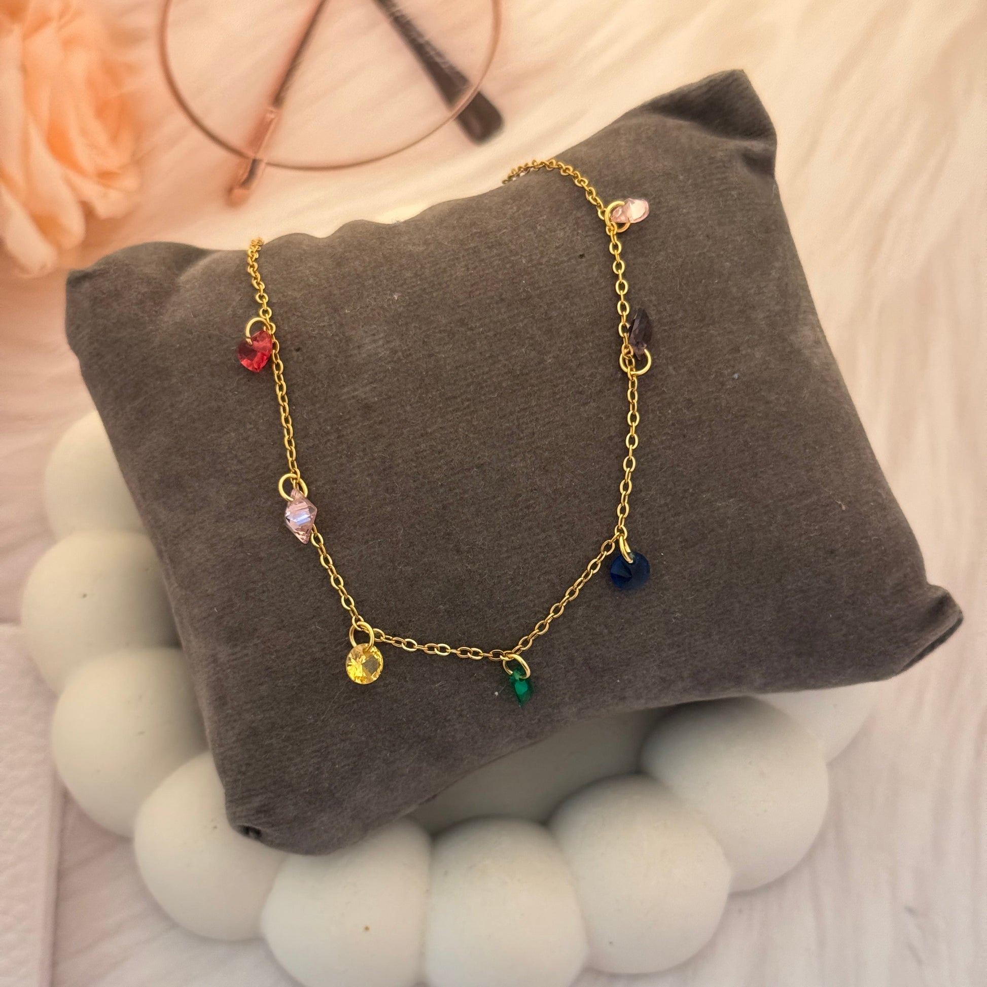 Gold bracelet with colorful beads on a gray pillow