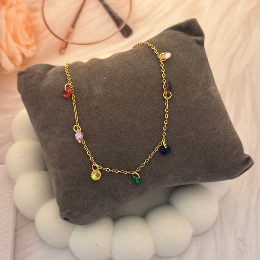 Gold bracelet with colorful beads on a gray pillow