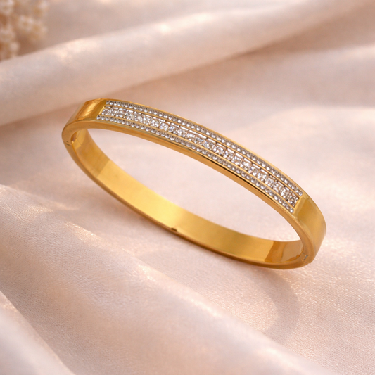Gold bracelet with embedded diamonds on a soft fabric background