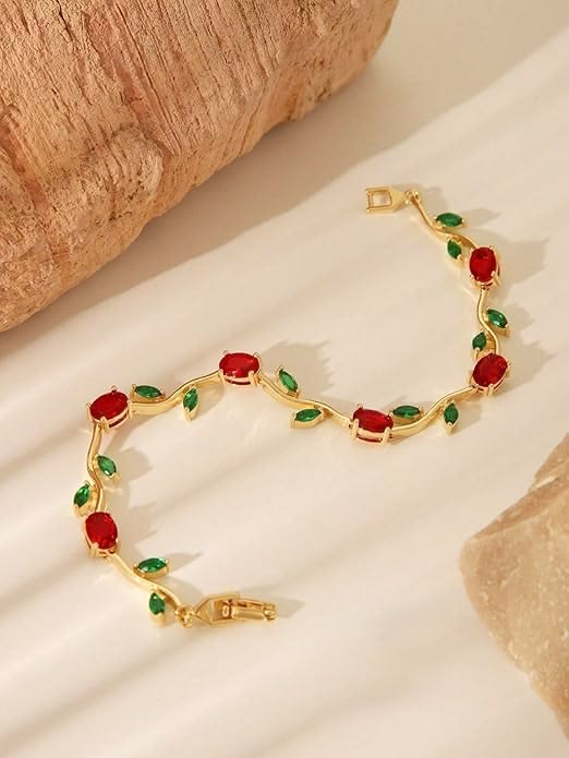Gold bracelet with red and green gemstones on a beige background