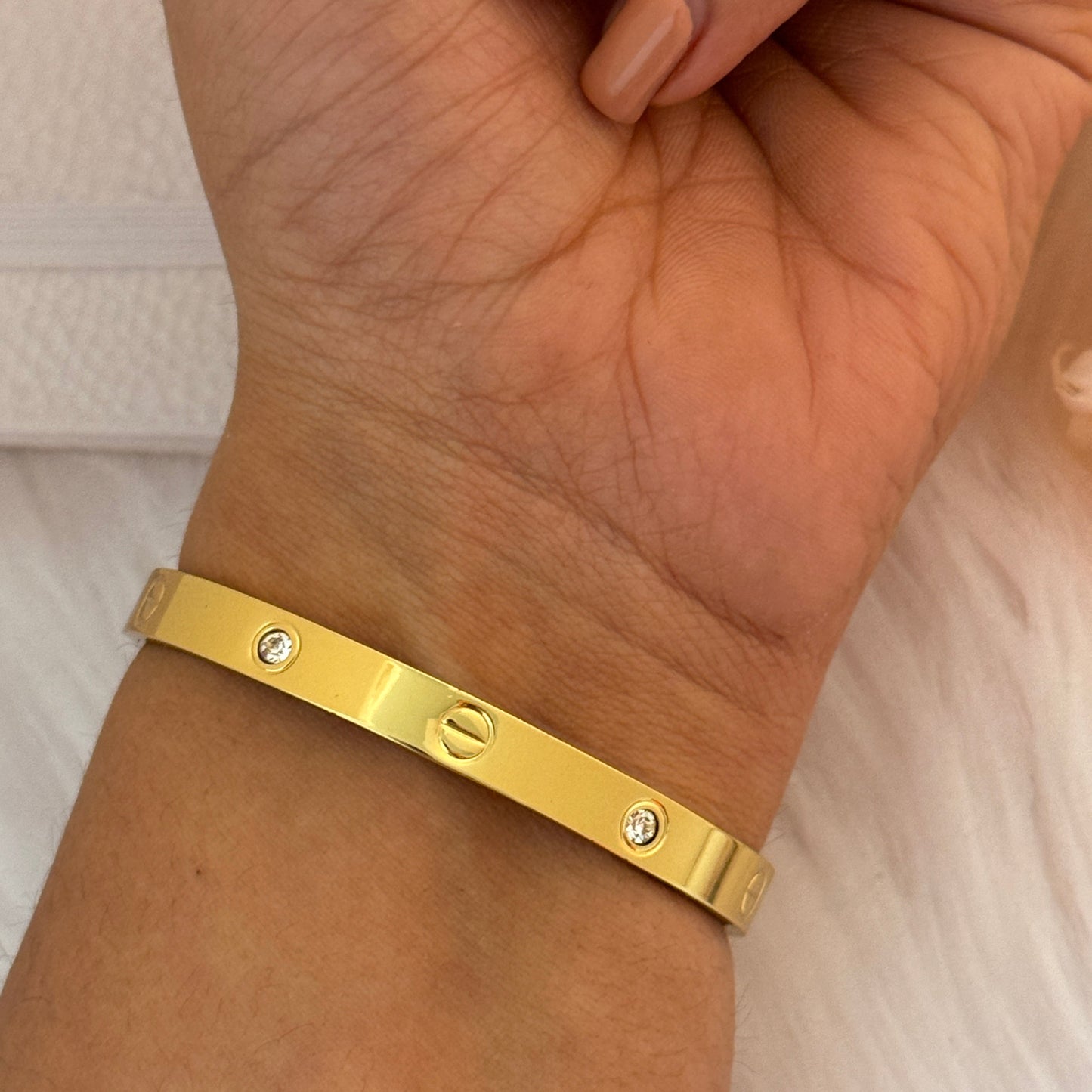 Gold bracelet on a wrist with a neutral background