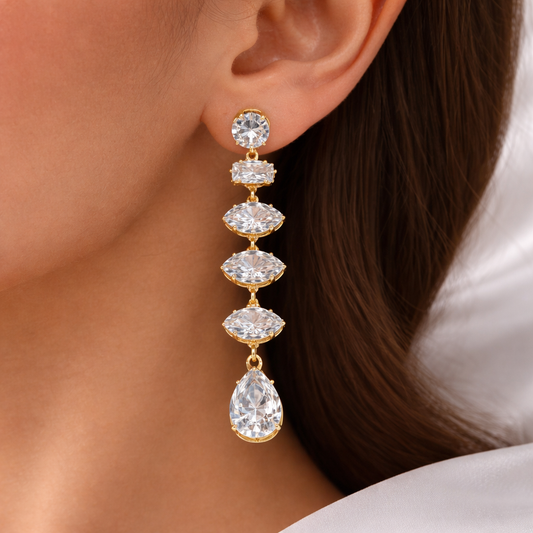 Gold earrings with clear gemstones worn by a person