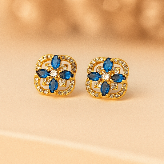 Gold earrings with blue gemstones on a beige background