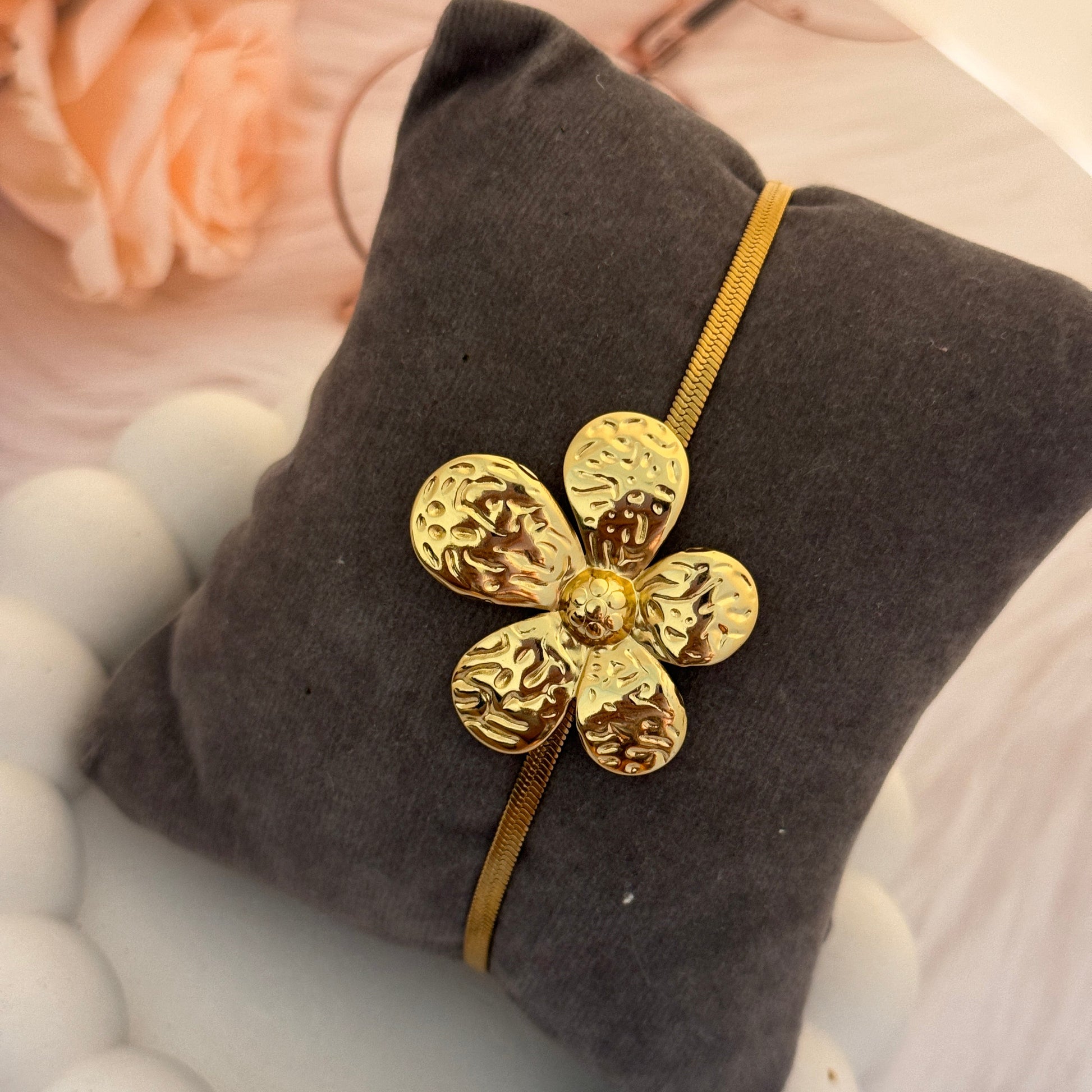 Gold flower-shaped hairband on a gray cushion with blurred floral background