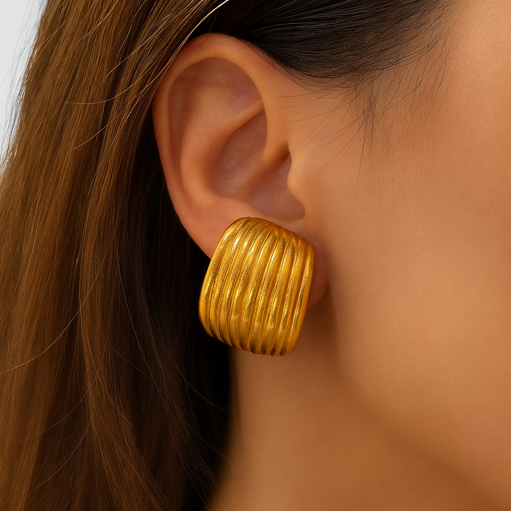 Gold hoop earring worn by a person with a neutral background