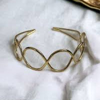 Gold infinity bracelet on a white fabric background