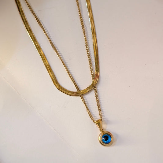Gold necklace with a blue gemstone pendant on a white background