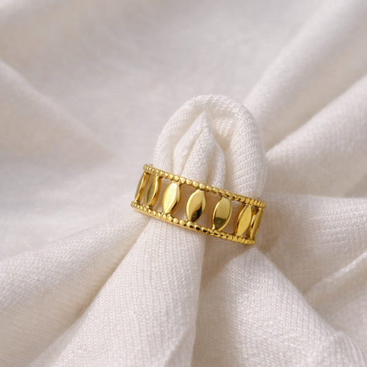 Gold ring with leaf design on a white fabric background